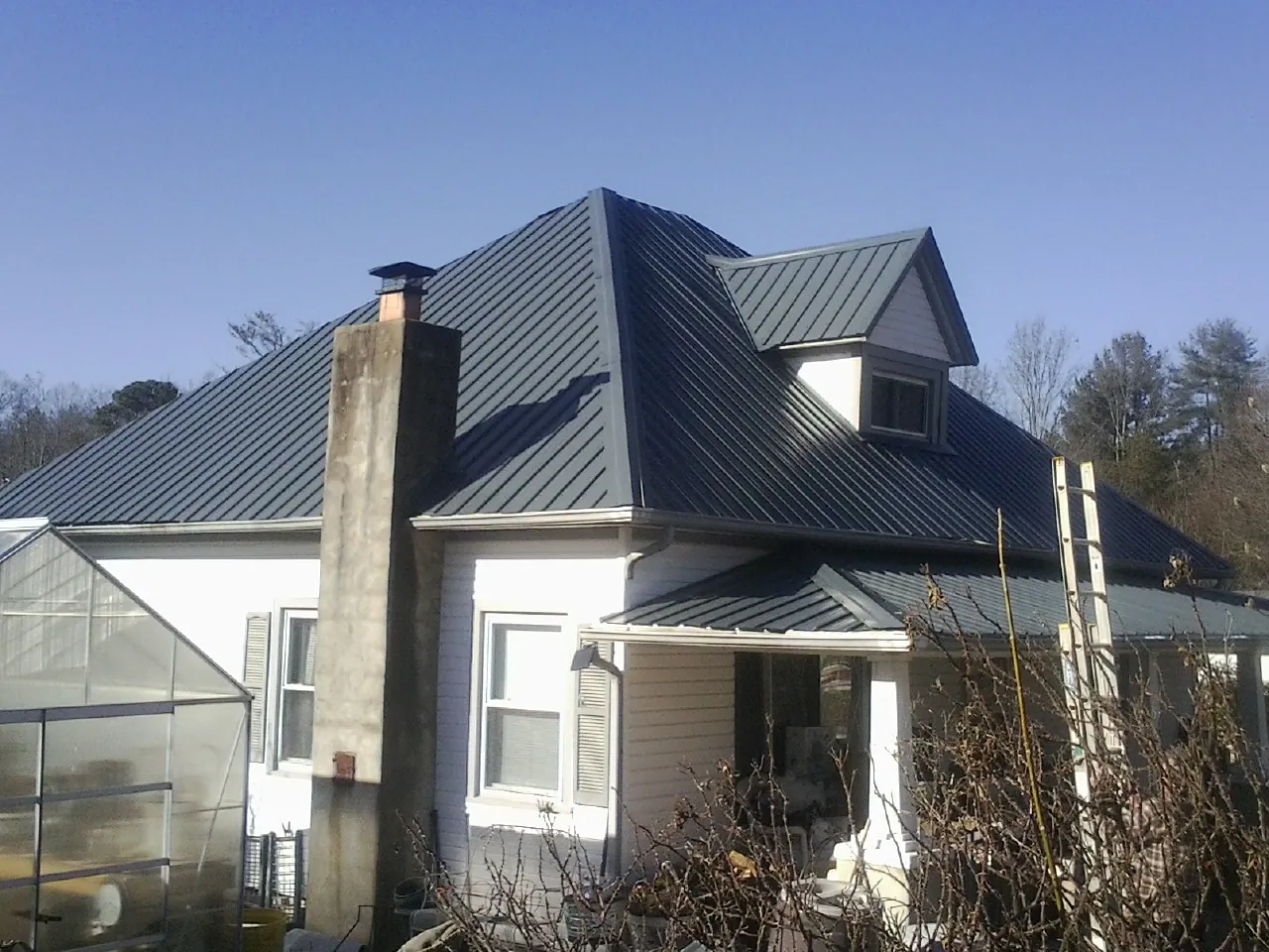 Dark blue standing seam metal roof on a white farmhouse with dormer — Slate & Tile Roof Repair by Roofing Brothers in Lookout Mountain