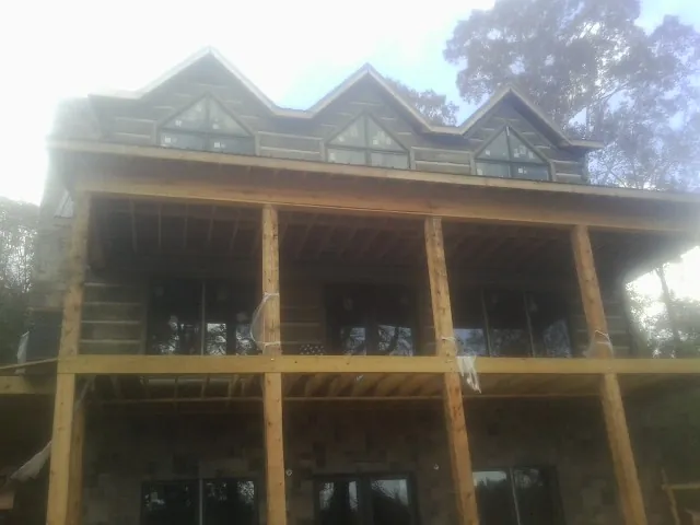 Dormers and porch framing on a large log home under construction — Roof Coating work by our crew in Lookout Mountain