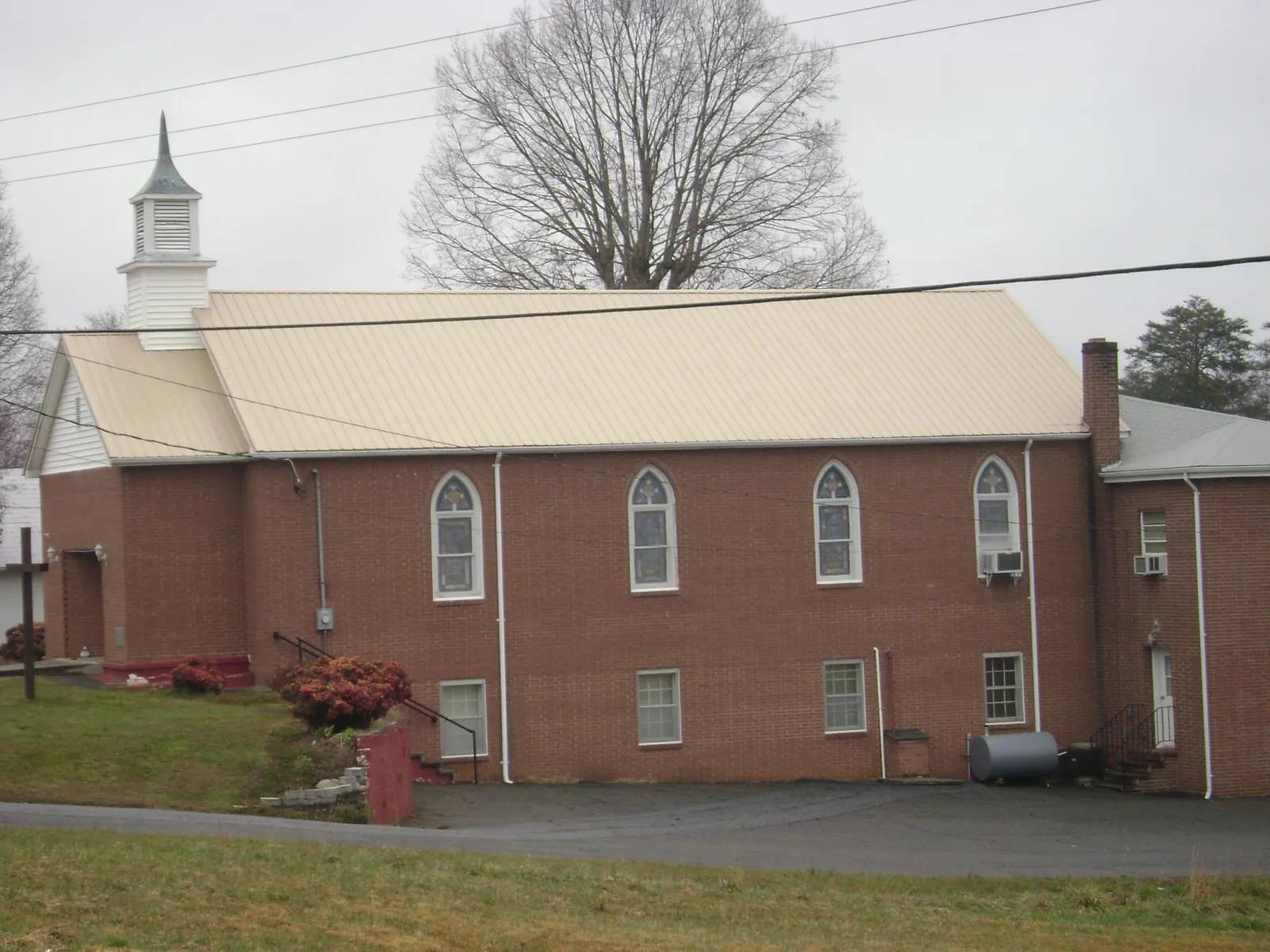 New tan metal roof on a brick church with a white steeple in Lookout Mountain