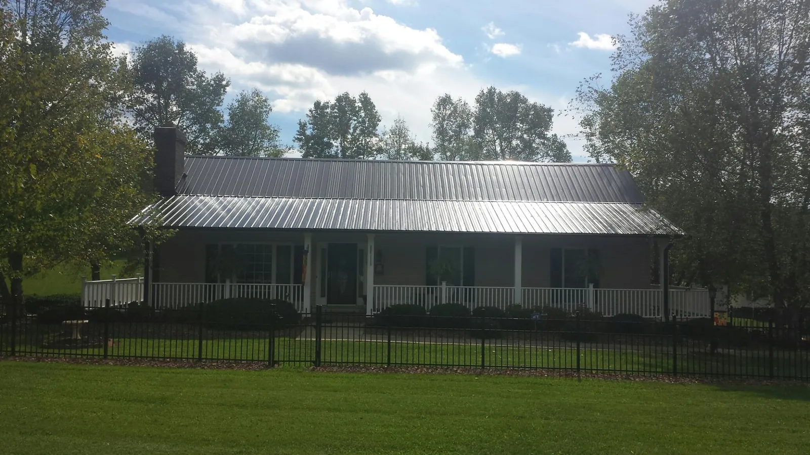 Gray metal roof on a brick ranch with a full width front porch — Gutter Guard Installation work by our crew in Lookout Mountain