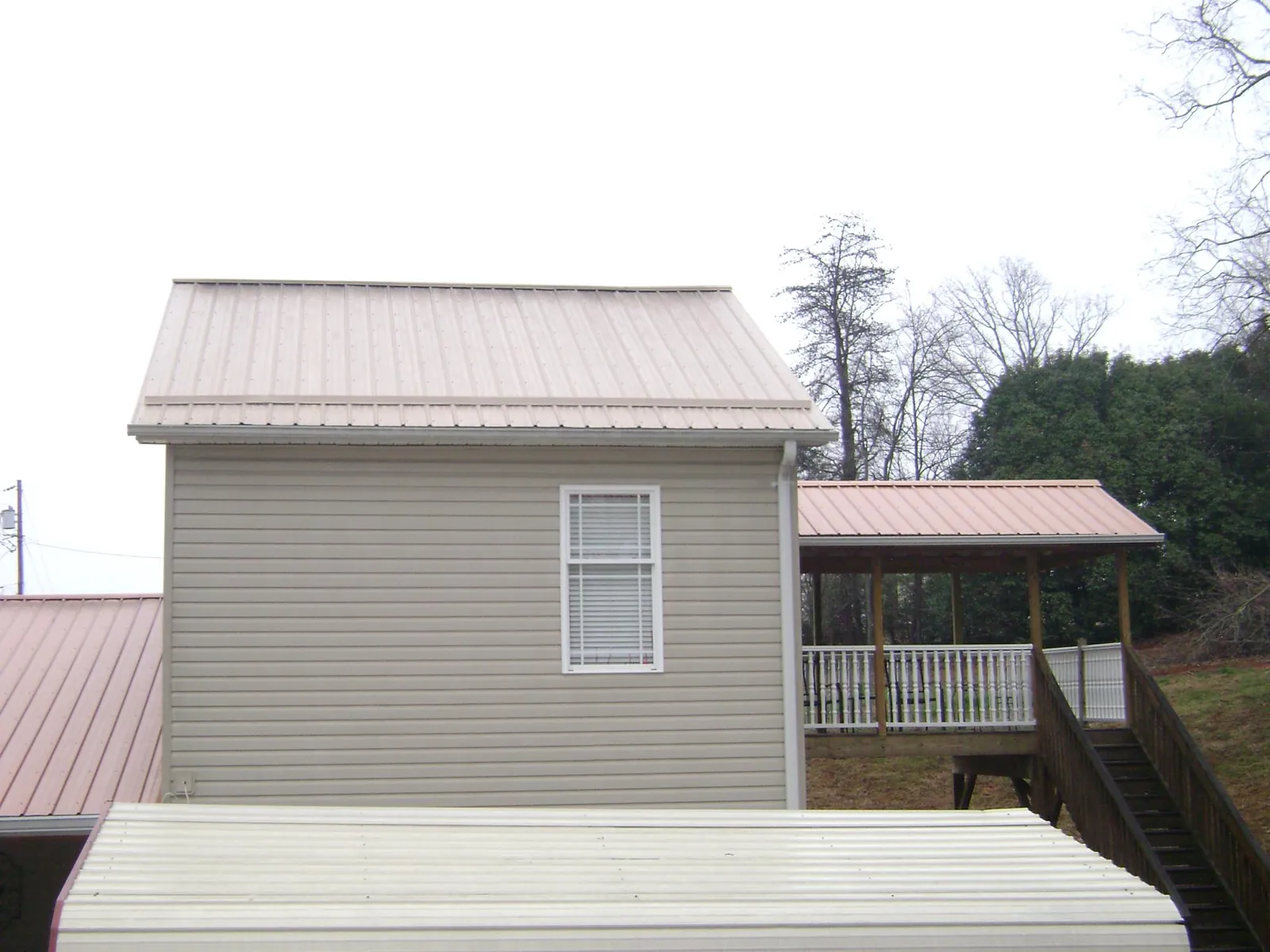 Tan metal roofs on a two story addition and attached porch, from a Roof Replacement job in Lookout Mountain