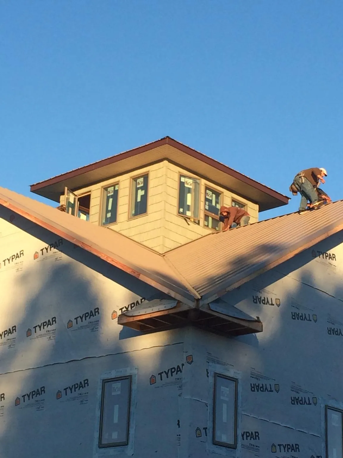 Roofers working around a rooftop cupola on a new metal roof at sunset — Roof Waterproofing in Lookout Mountain by Roofing Brothers